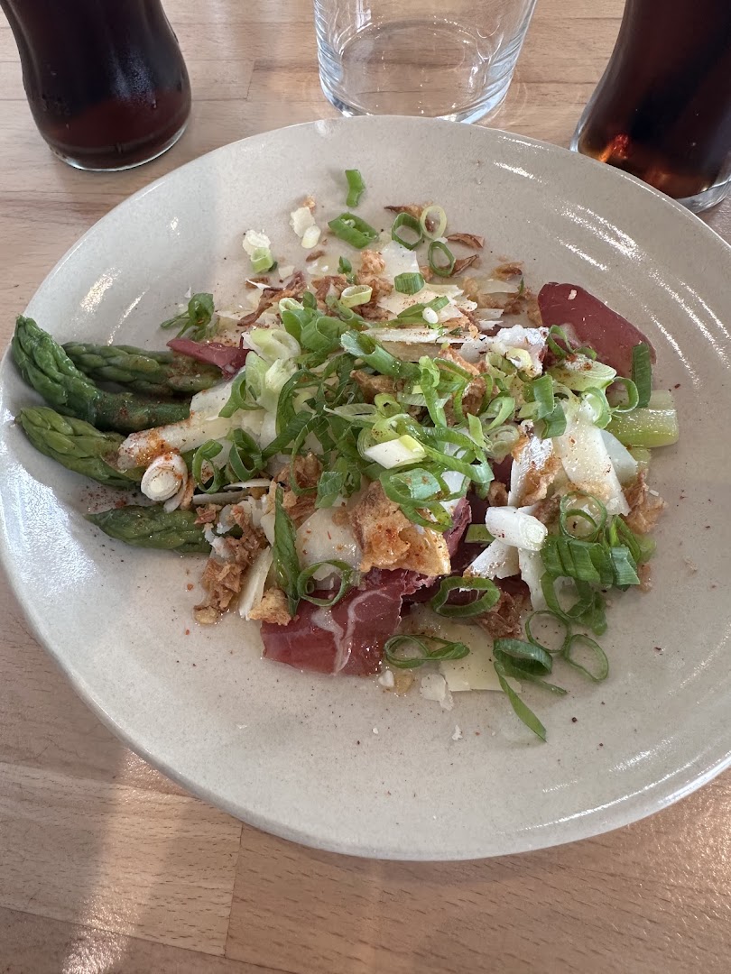 Une assiette de légumes blancs, asperges vertes et viande séchée