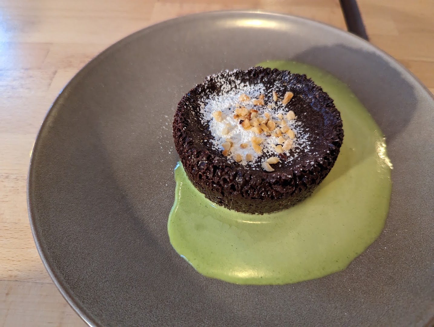 Un petit gâteau au chocolat accompagné d’une sauce verte